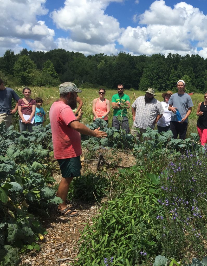 John Wright teaching in his garden to a group of people. 